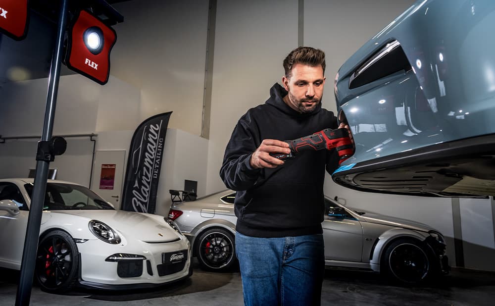 En blå bil blir polert av en bilpleier ved hjelp av FLEX PXE smart poleringsmaskin.