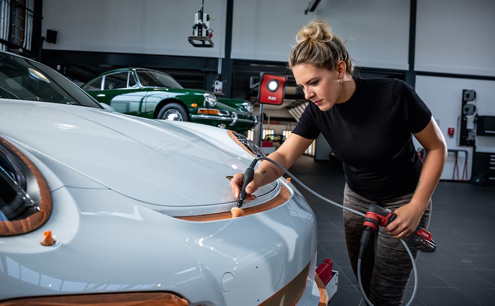 En bulk på en hvit bil poleres ved hjelp av en fleksibel aksel og en kjeglesvamp.