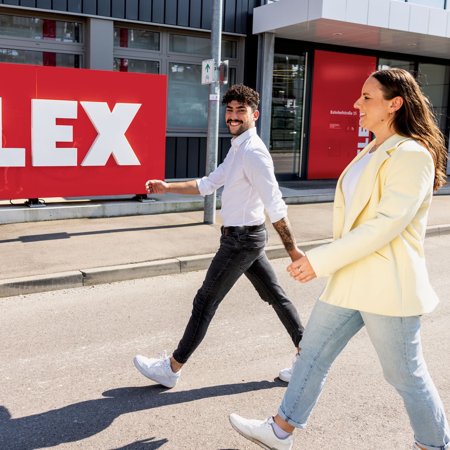 Mitarbeitende vor dem FLEX Firmengebäude mit FLEX Logo.