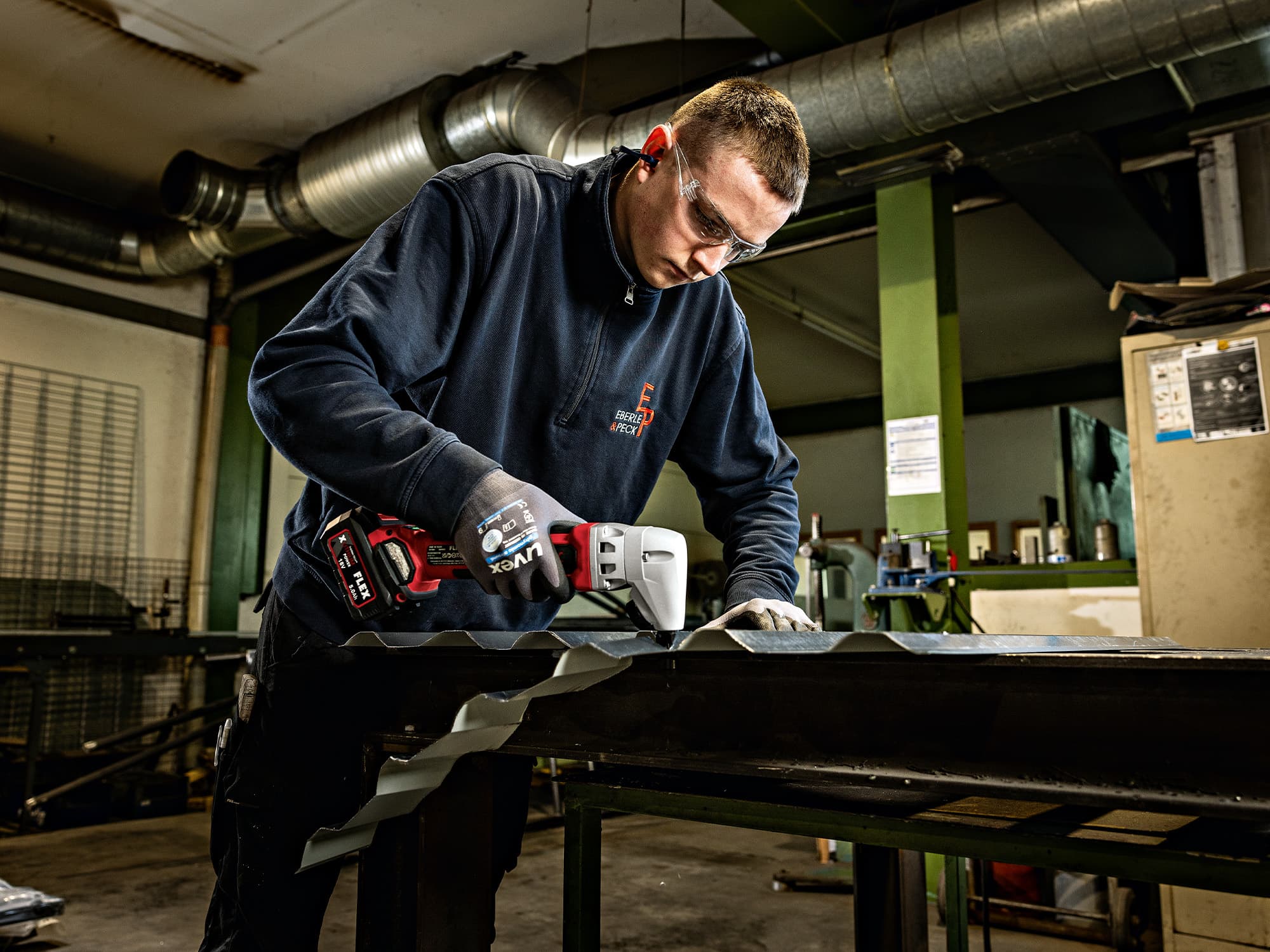 Ein Blech wird von einem Handwerker mit dem FLEX Knabber geschnitten.