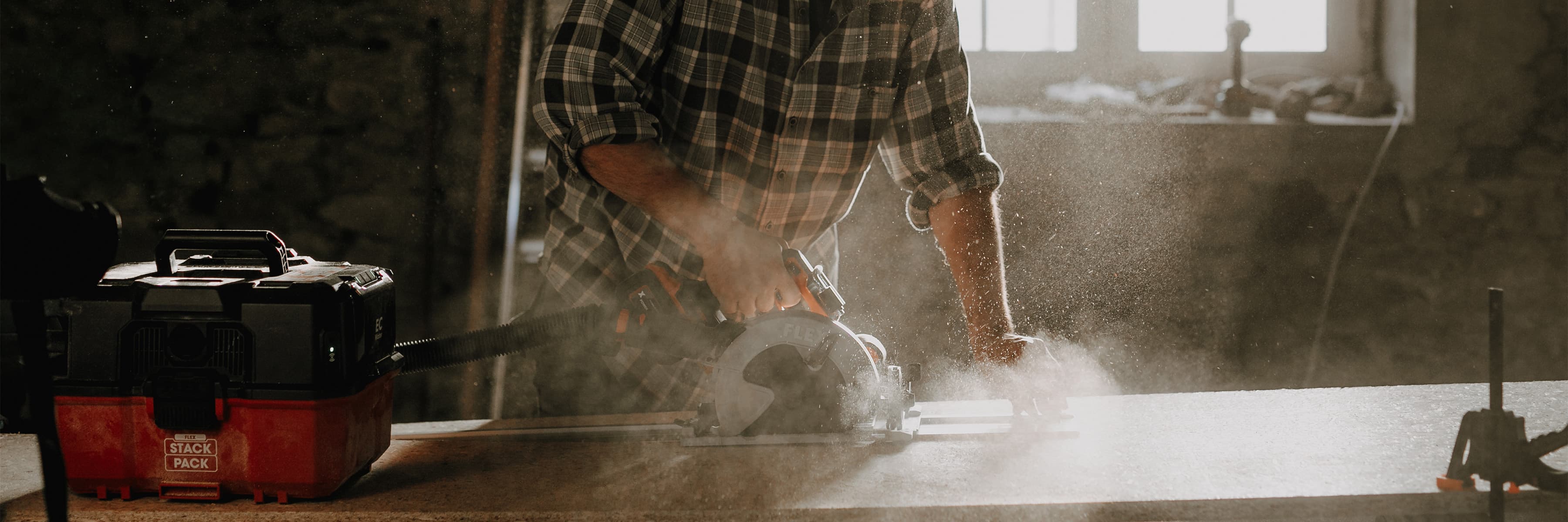 Mit einer Handkreissäge wird Holz von einem Handwerker zugesägt.