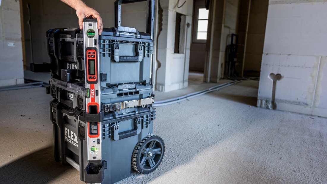 STACK PACK™ transport case system with attached spirit level on a construction site. The robust and stackable solution enables safe tool organisation and easy transport.