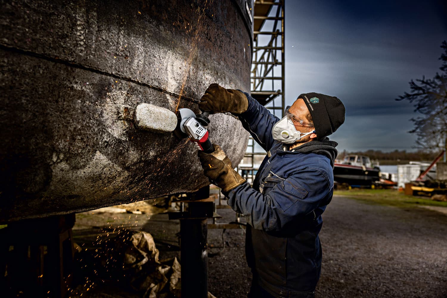 Craftsman sanding the hull of a boat outdoors using a FLEX angle grinder with deadman function