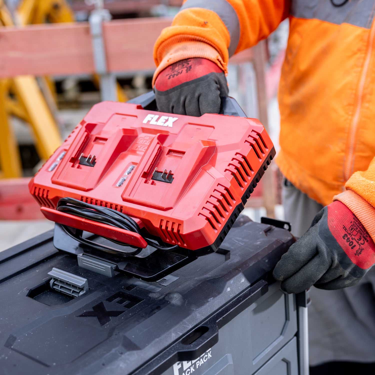 Handwerker platziert das FLEX Doppel-Ladegerät CA SP 2x 12-18 auf einer STACK PACK™ Werkzeugbox. Die Ladestation ermöglicht das gleichzeitige Laden von zwei FLEX Akkus und ist kompatibel mit dem modularen STACK PACK™ System.