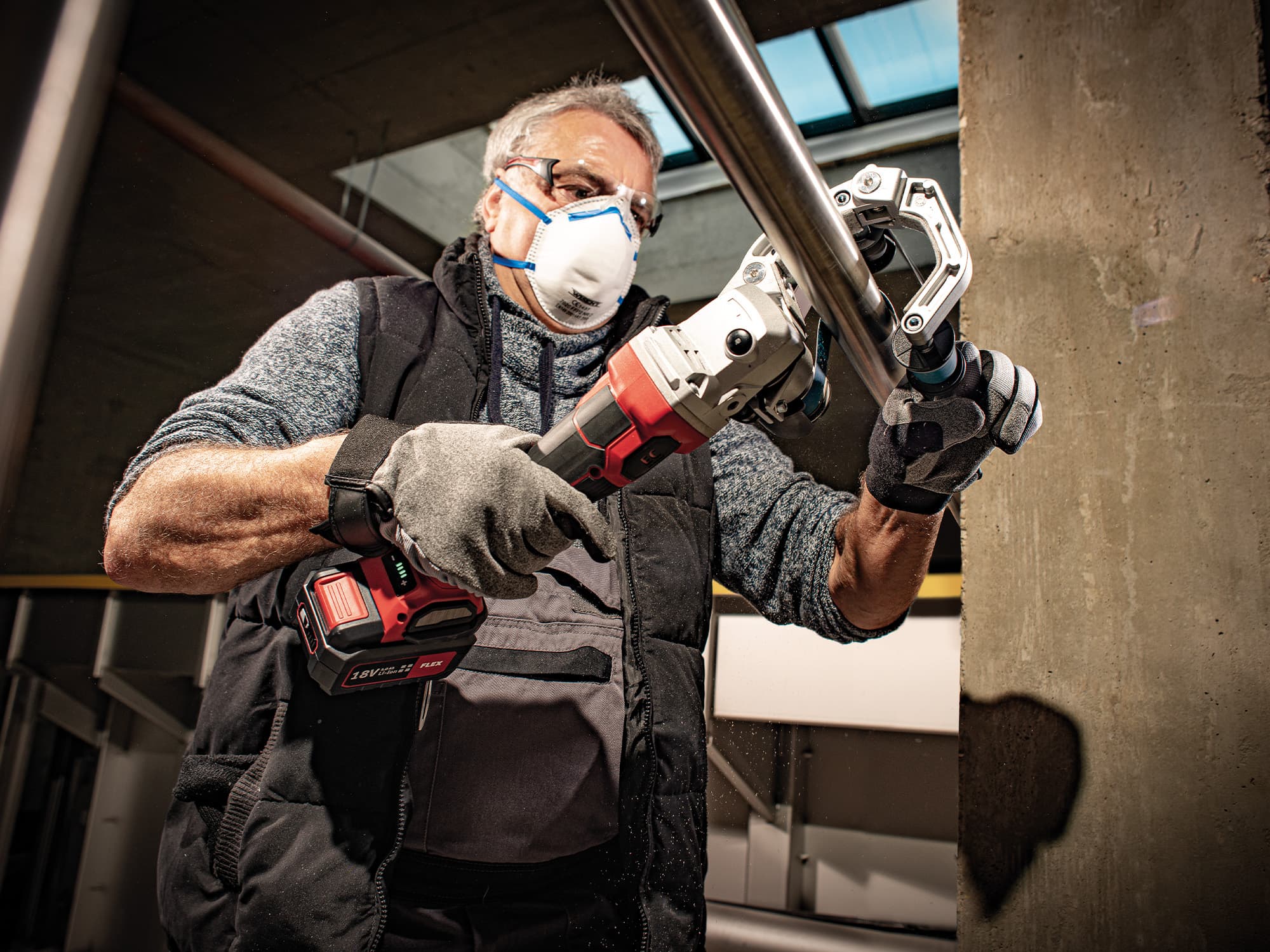 Ein Metallrohr wird von einem Handwerker mit dem FLEX Rohrbandschleifer bearbeitet.