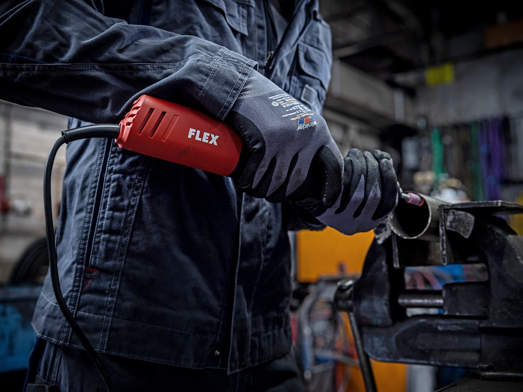 Mit dem kabelgebundenen Geradschleifer von FLEX wird ein rundes Metallrohr an der Schnittkante geschliffen.