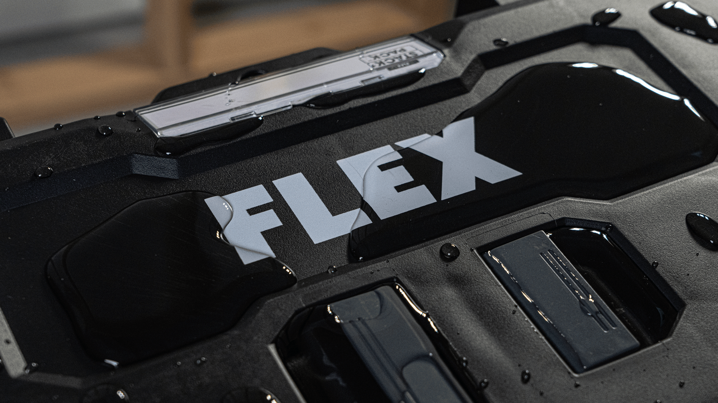 Nahaufnahme eines STACK PACK™ Transportkoffers mit FLEX-Logo und Wassertropfen. Das robuste IP 65-geschützte Gehäuse sorgt für Staub- und Wasserschutz auf der Baustelle.