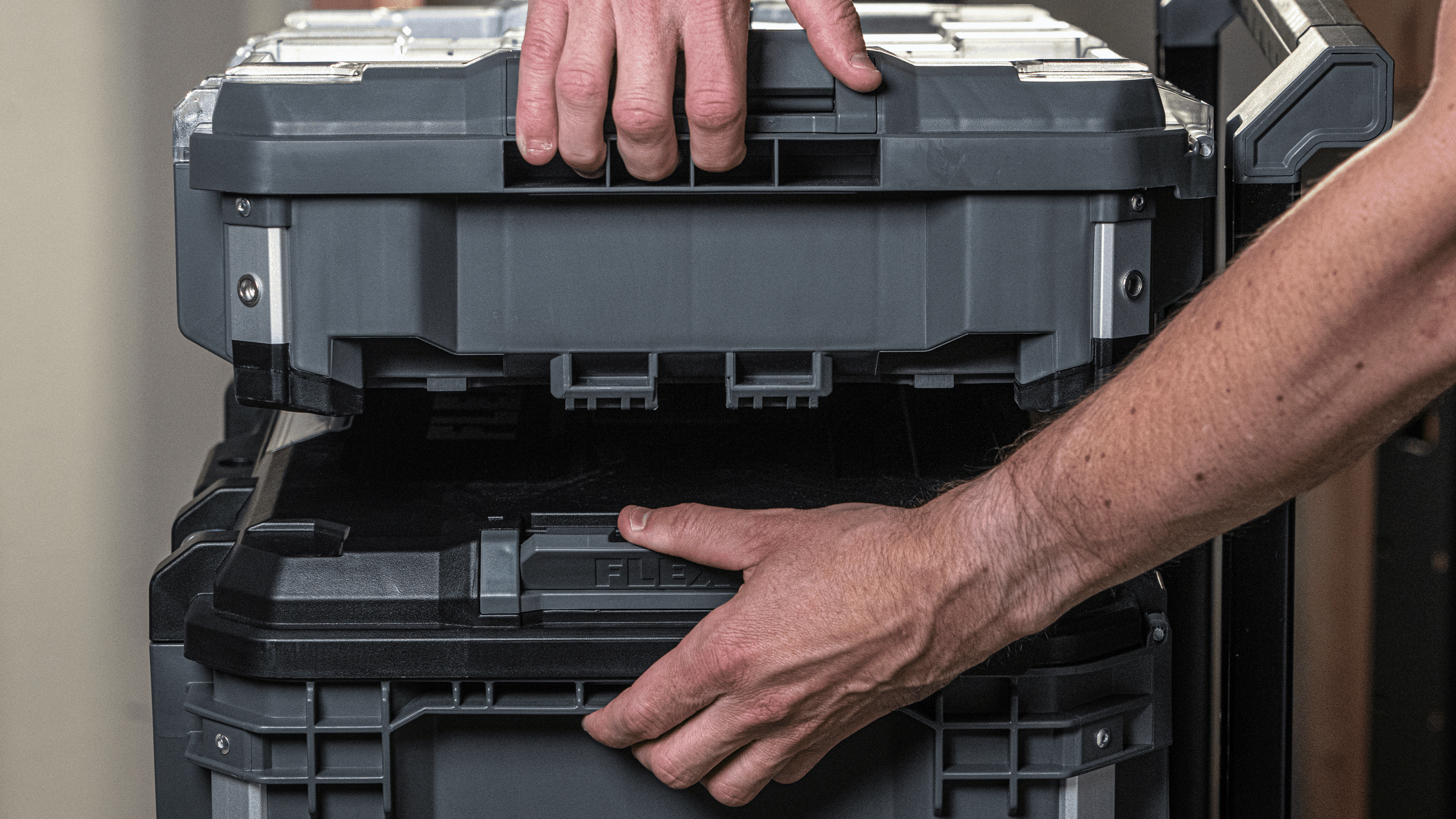 Handwerker verbindet zwei STACK PACK™ Werkzeugboxen mit dem praktischen Schnellverschluss. Die stapelbaren Boxen ermöglichen eine flexible und sichere Werkzeugaufbewahrung.